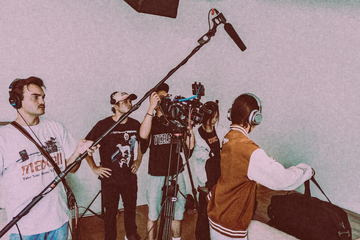 Camera and sound crew at work against a pale wall
